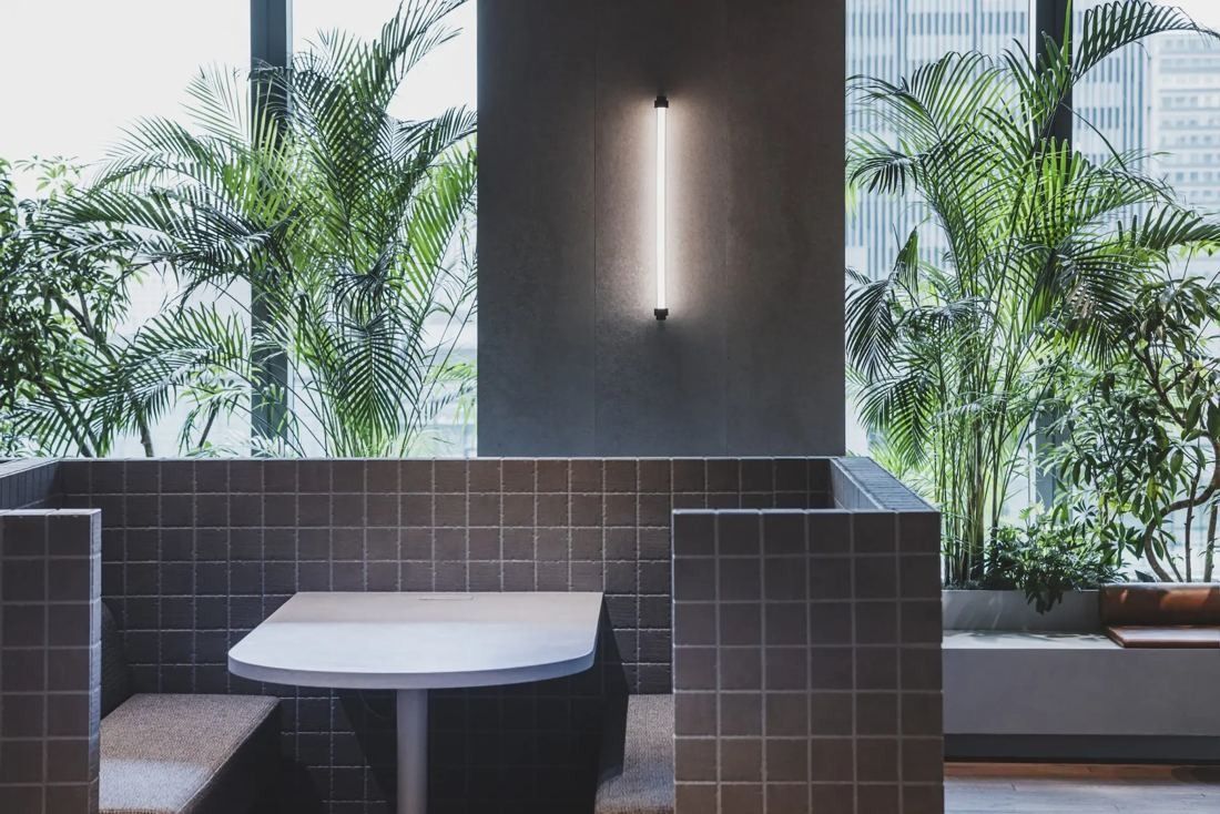 ITOKI: Tiled booth with a table set against tall plants and a window