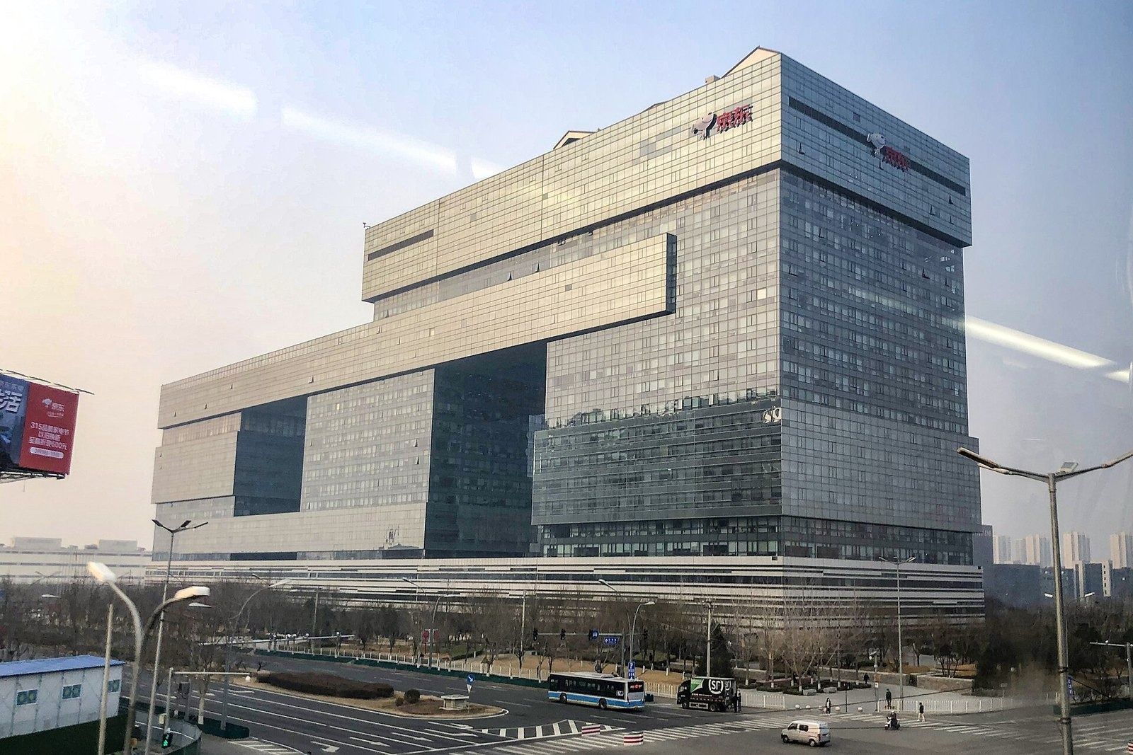 JD.com: Glass headquarters building beside a road under a hazy sky