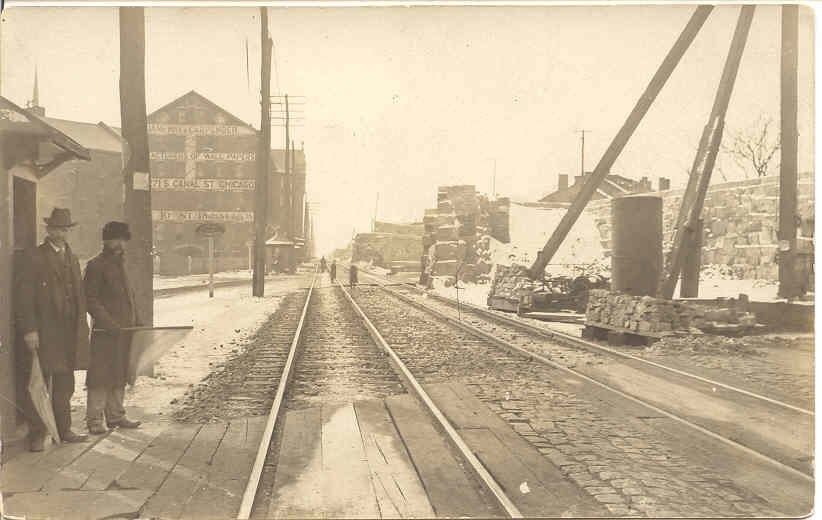 A sepia photo of a railroad street and an early factory building
