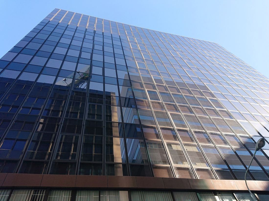 Kao: A dark glass curtain wall reflecting the sky, seen from below