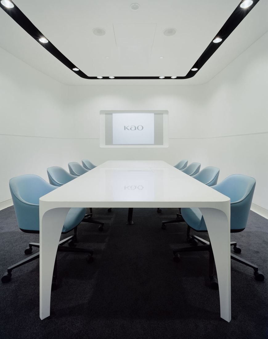 Kao: A long white table with light blue chairs facing a projection screen