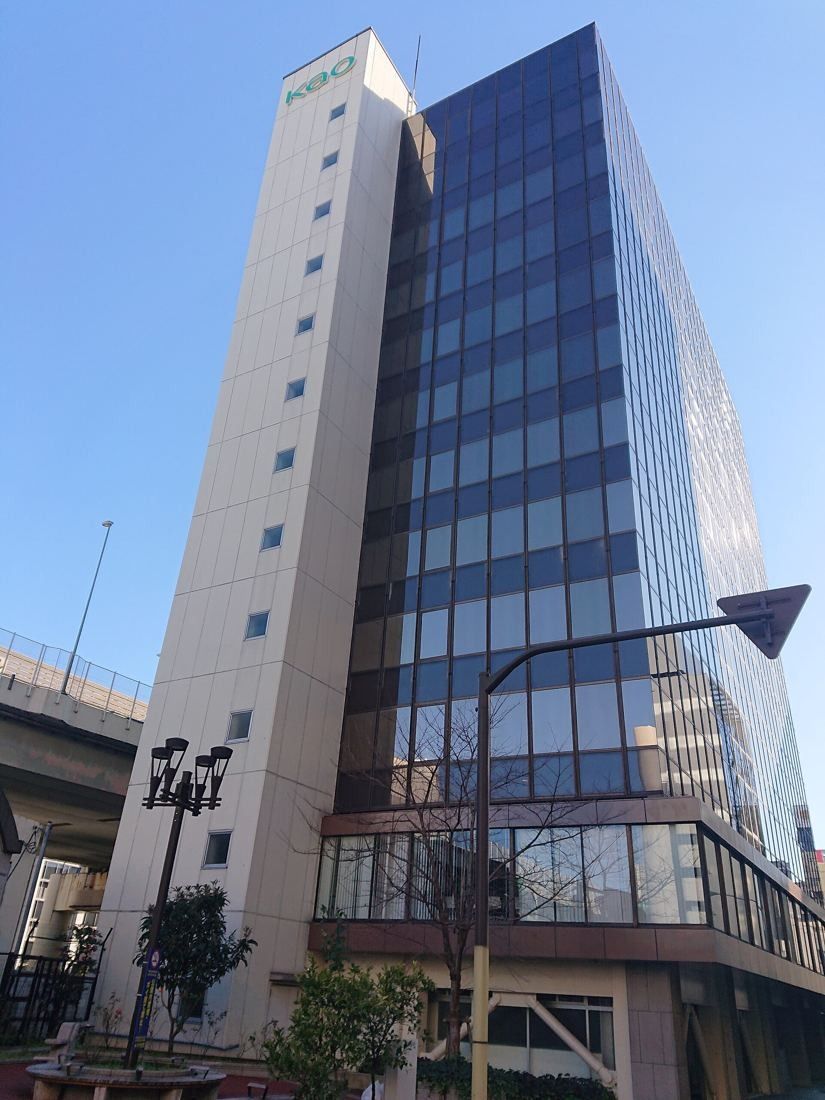 Kao: A tall tower with white and dark glass façades against a blue sky