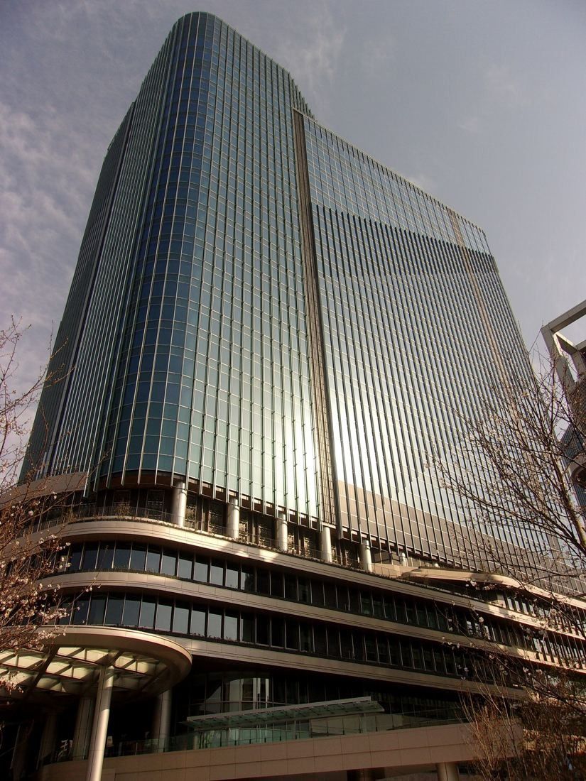 KDDI: A tall glass tower on a layered podium, seen from below
