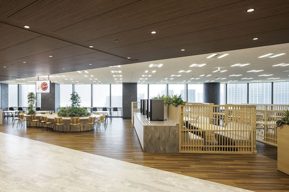 KDDI: A wood-floored space with tables, plants and wooden lattice partitions by the windows