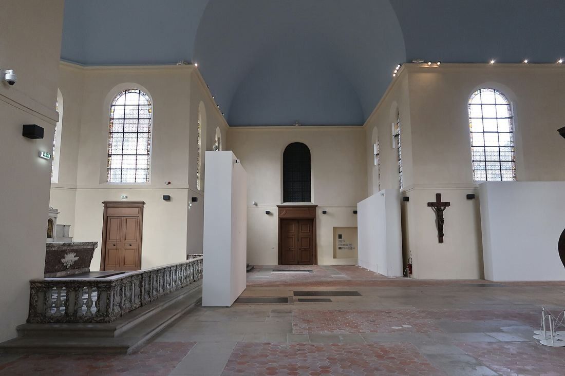 Kering: Chapel nave with pale walls, arched windows, a balustrade and free-standing white partitions
