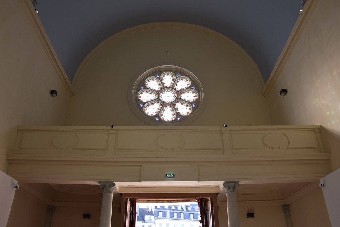 Kering: Chapel rose window above a gallery and open doorway