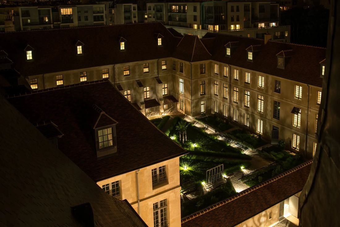 Kering: Courtyard garden lit at night, seen from above between historic wings with lit windows