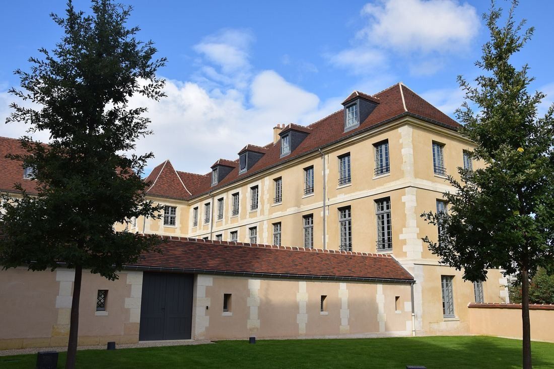Kering: Long stone wing with dormers behind a lawn and trees
