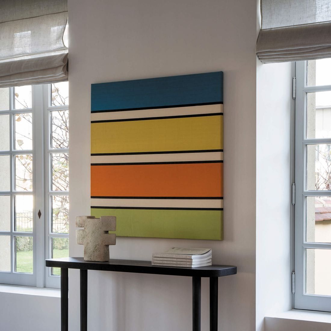 Kering: Striped colourful painting above a slim console between two windows