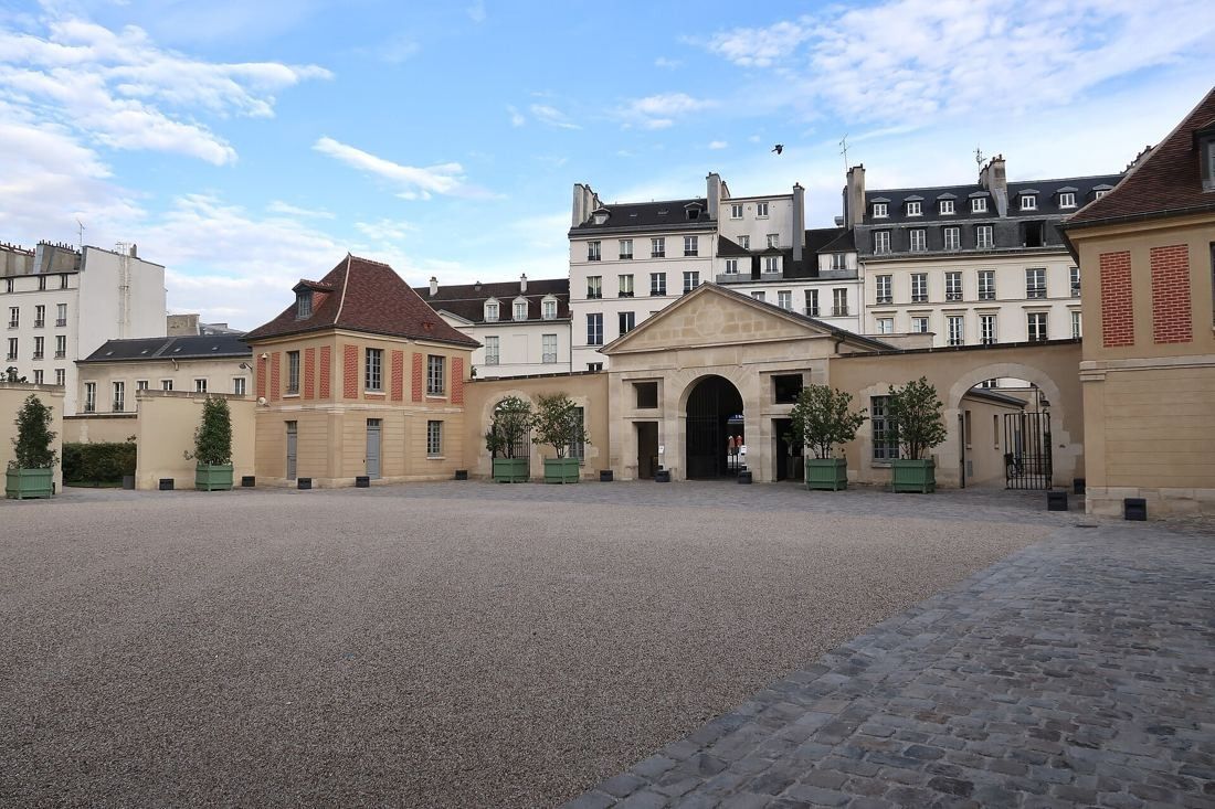 Kering: Wide paved courtyard with a columned entrance gate between two pavilions
