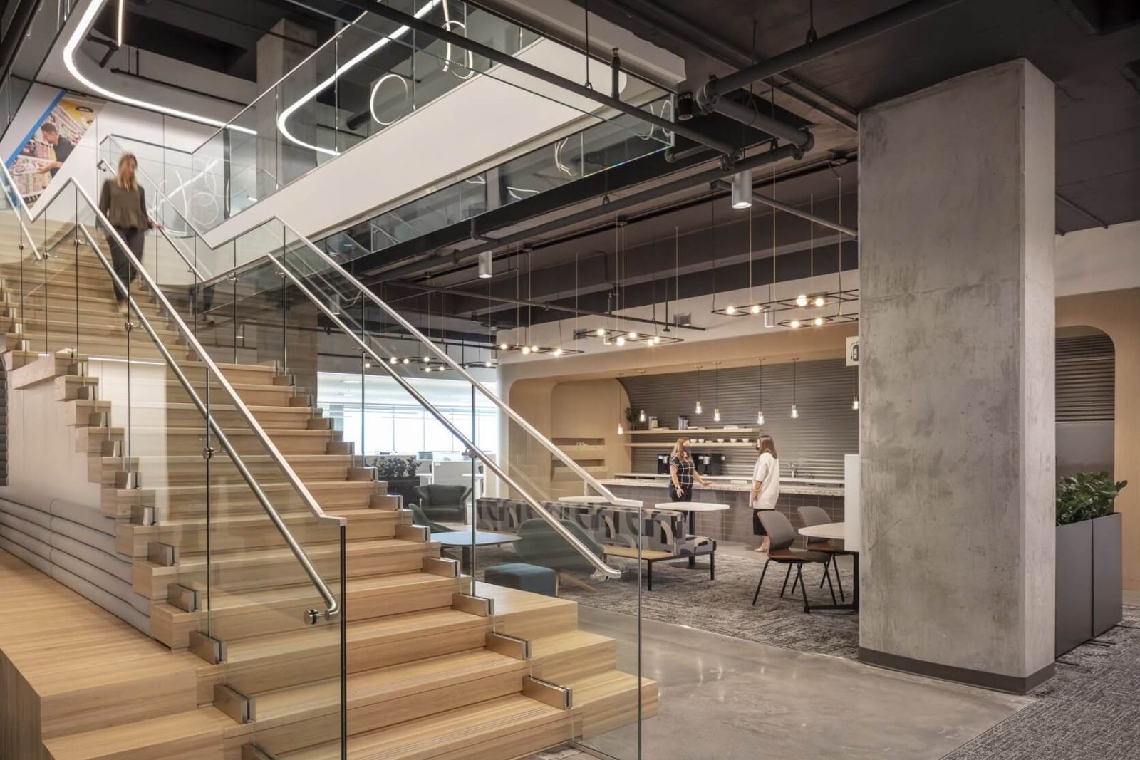 Keurig Dr Pepper: A glass-railed stair leading down to a café seating area with concrete columns
