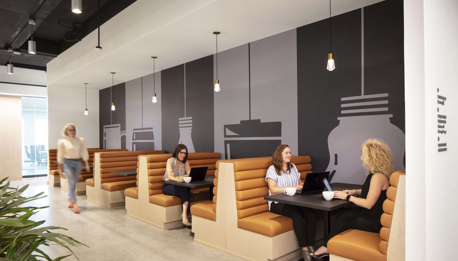 Keurig Dr Pepper: A row of orange booths along a grey wall painted with bottle shapes