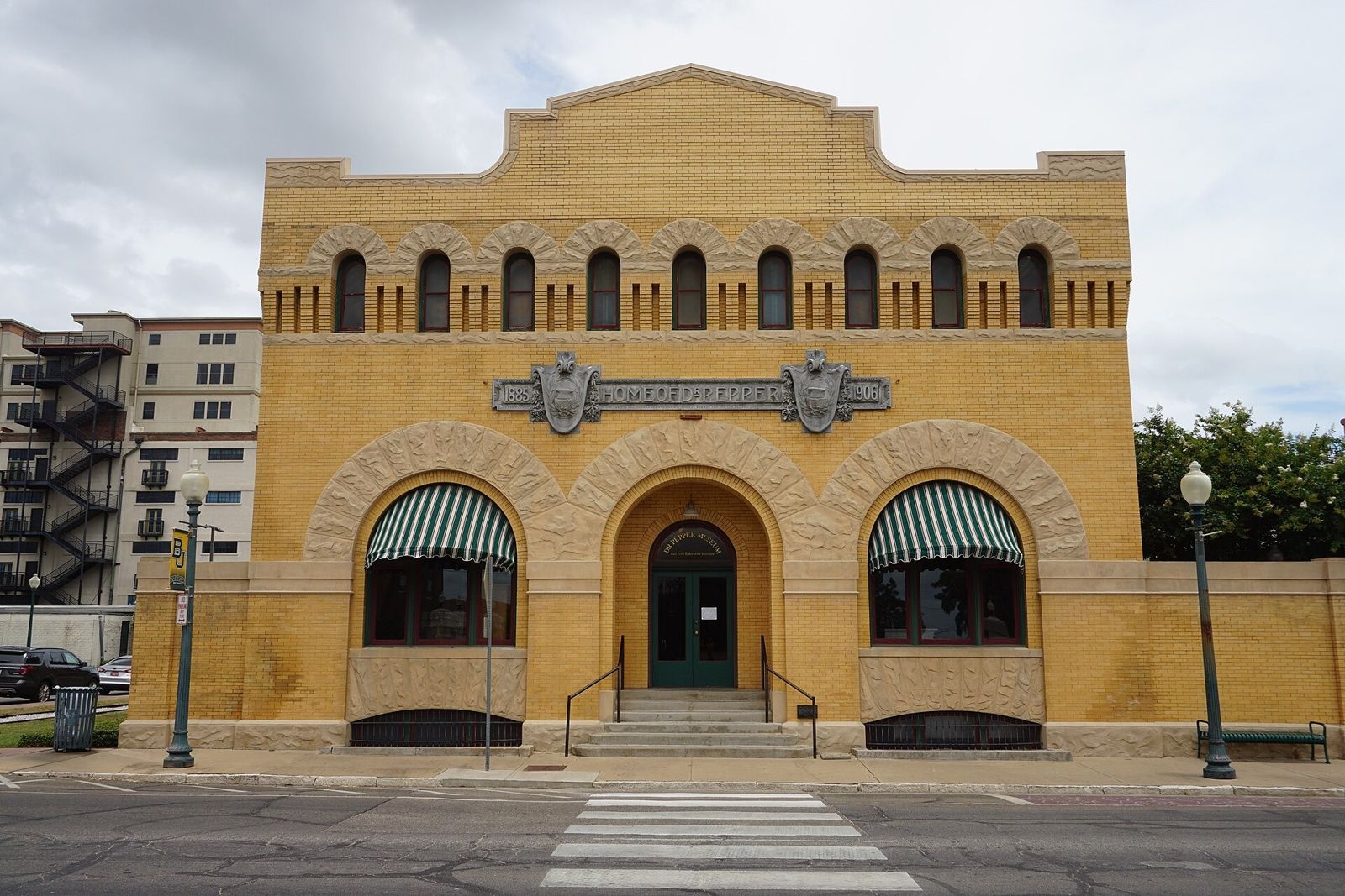 A two-story red brick industrial building with arched windows on a street corner