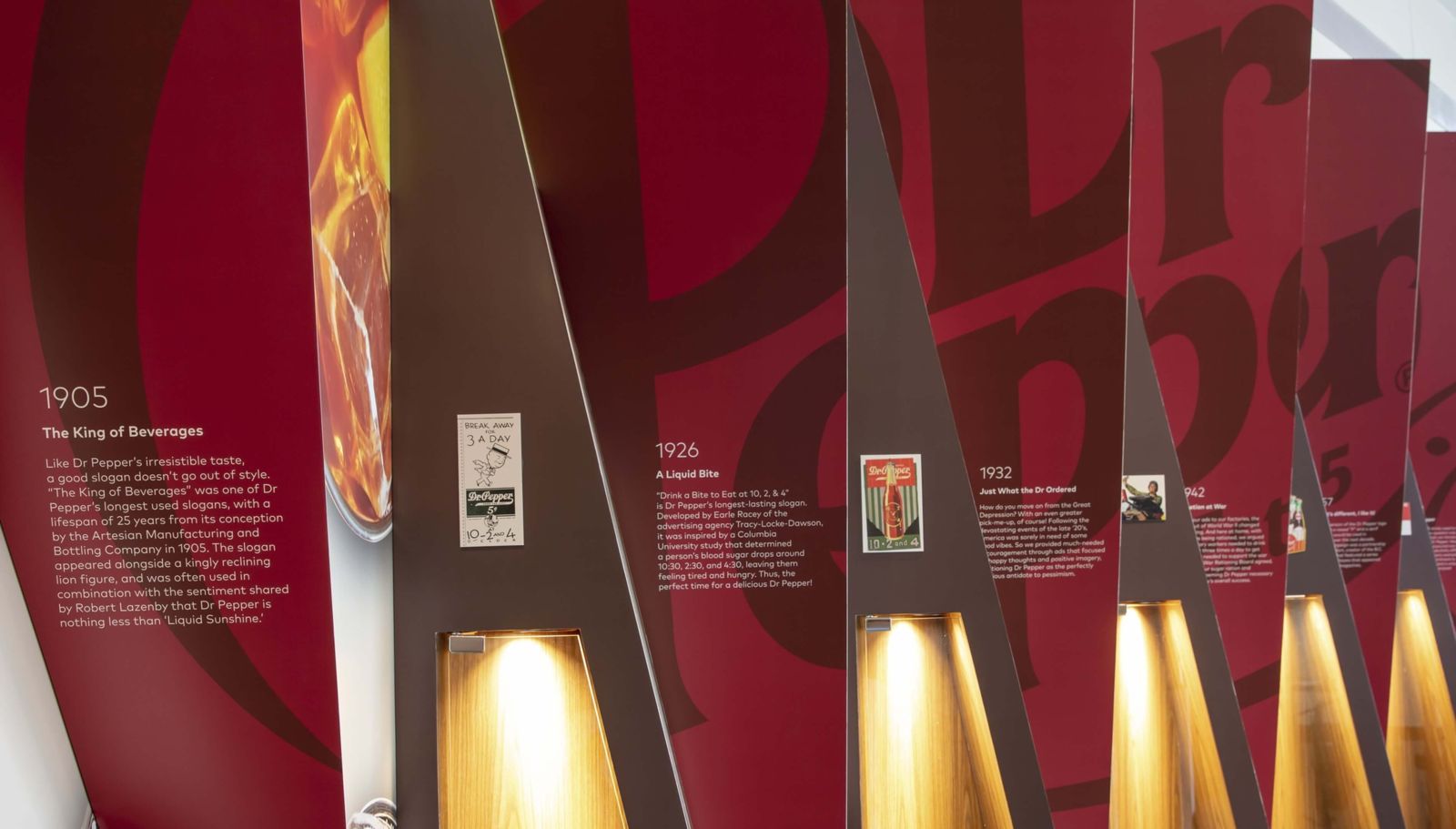 Keurig Dr Pepper: Angled red panels with dates and old Dr Pepper adverts lit from below