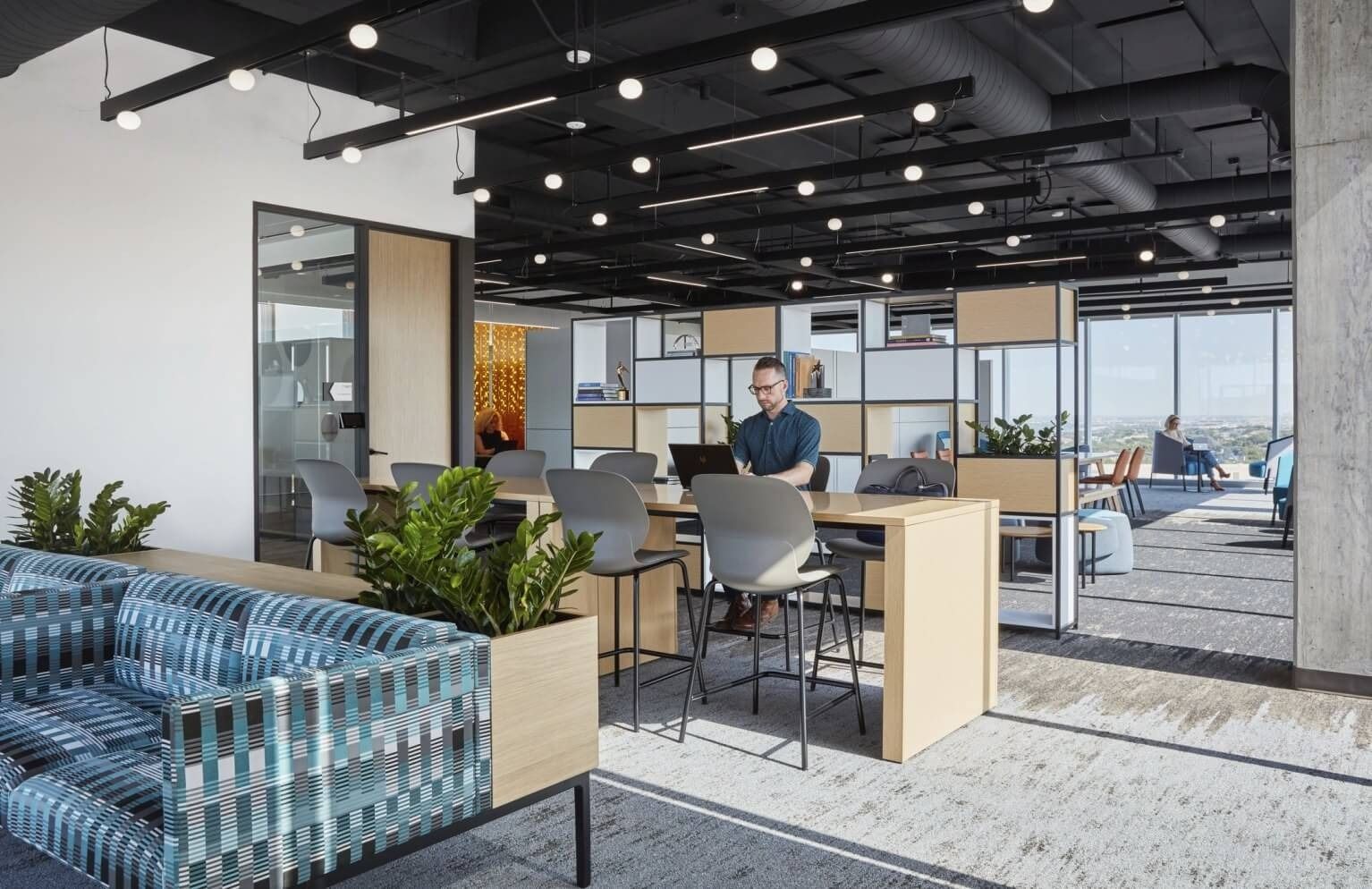 Keurig Dr Pepper: Blue sofas and open desks under an exposed black ceiling by tall windows