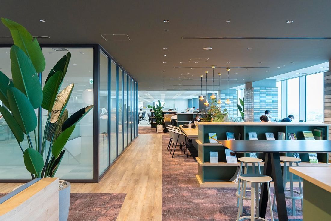 Kirin Holdings: Aisle between low bookshelves and high tables leading to the windows