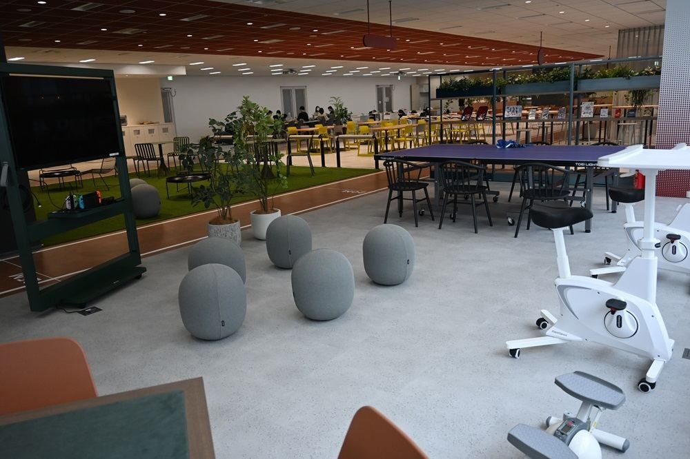 Kirin Holdings: Area with table tennis tables, grey balance balls and exercise bikes on a light floor
