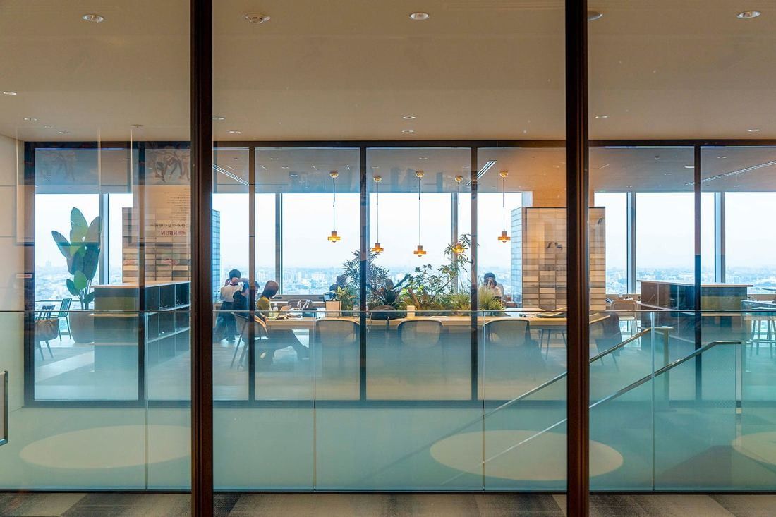Kirin Holdings: Glass partition looking into a library area with bookshelves and city windows