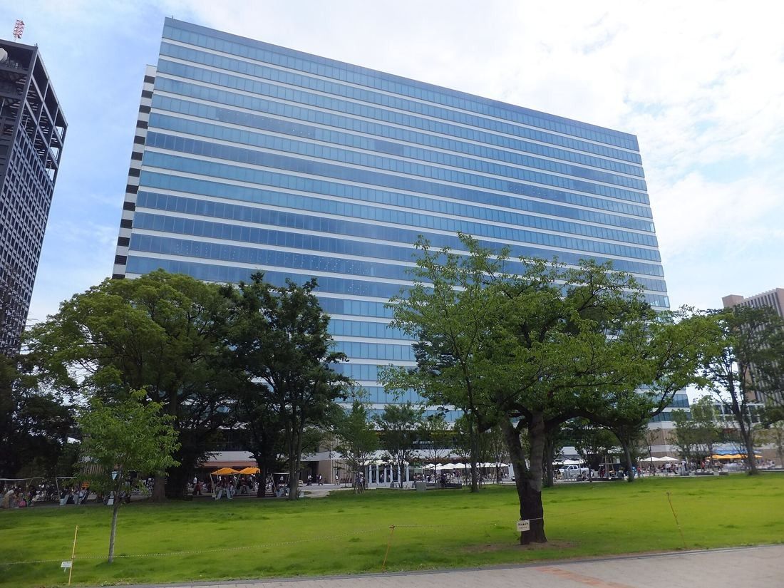 Kirin Holdings: Glass tower seen across a park lawn with large trees