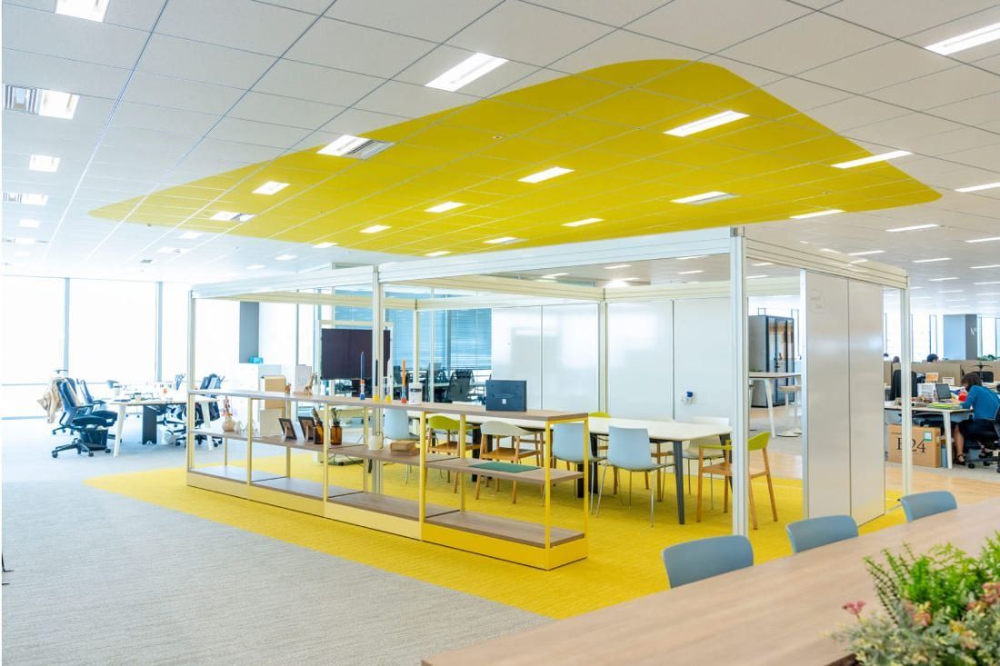 Kirin Holdings: Glass-walled meeting space under a yellow ceiling panel on a yellow floor