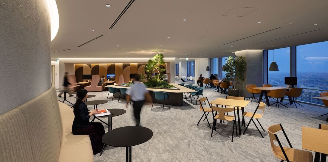 Kirin Holdings: Lounge with curved upholstered walls, café tables and a view over the city