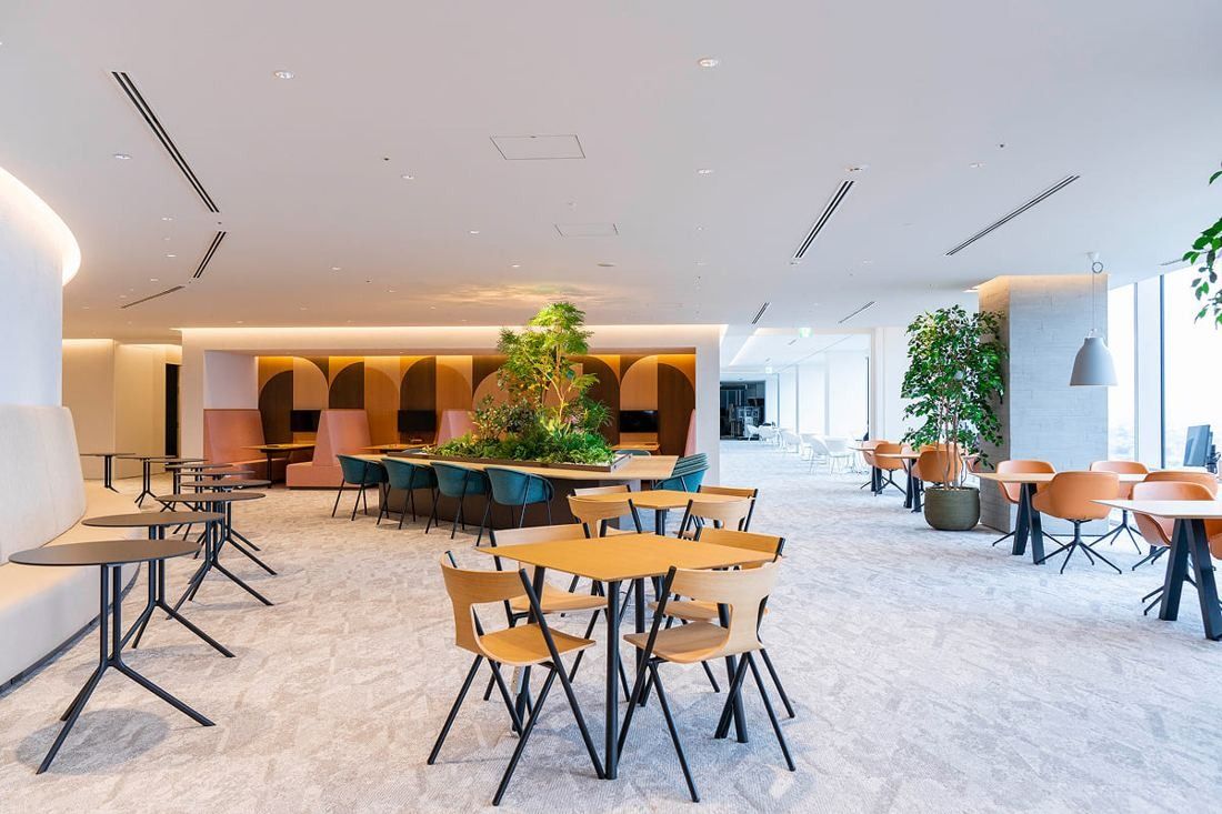 Kirin Holdings: Lounge with round café tables, orange chairs and arched booth seating