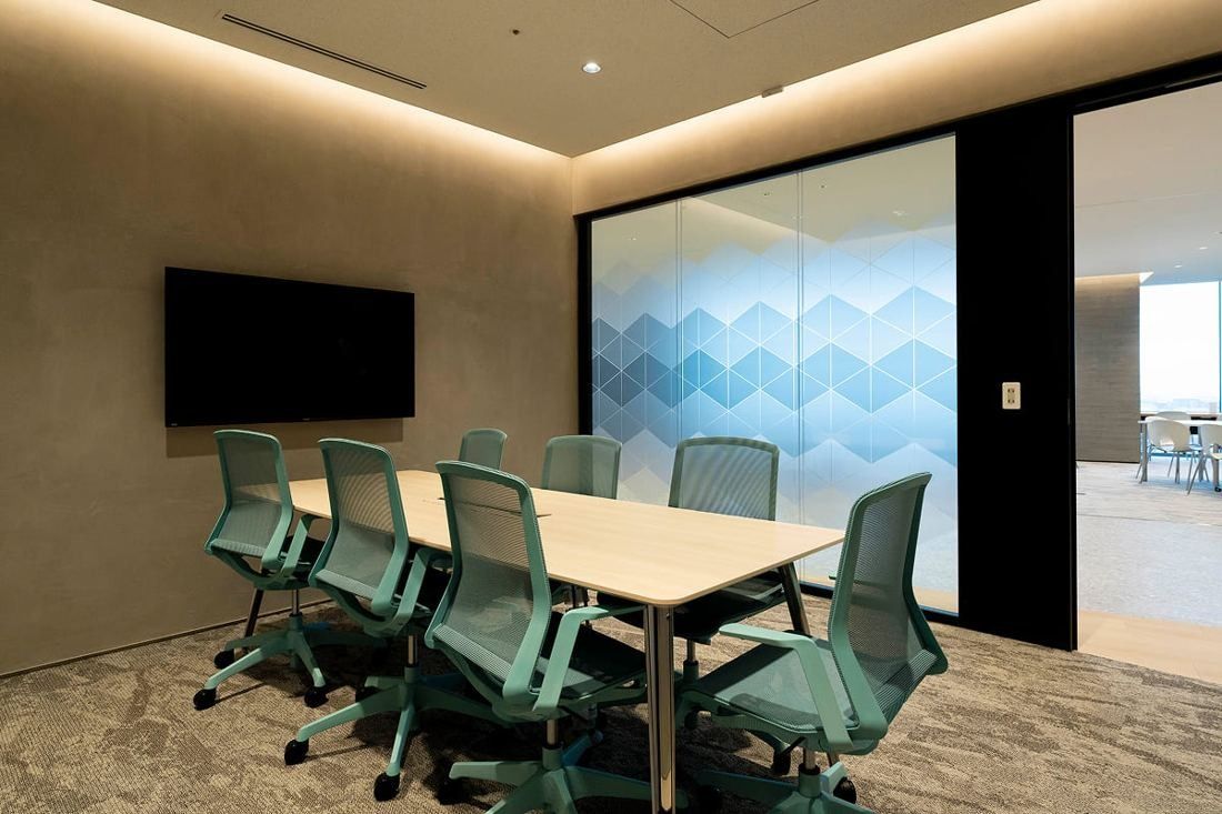 Kirin Holdings: Meeting room with a long table, green mesh chairs and a wall screen