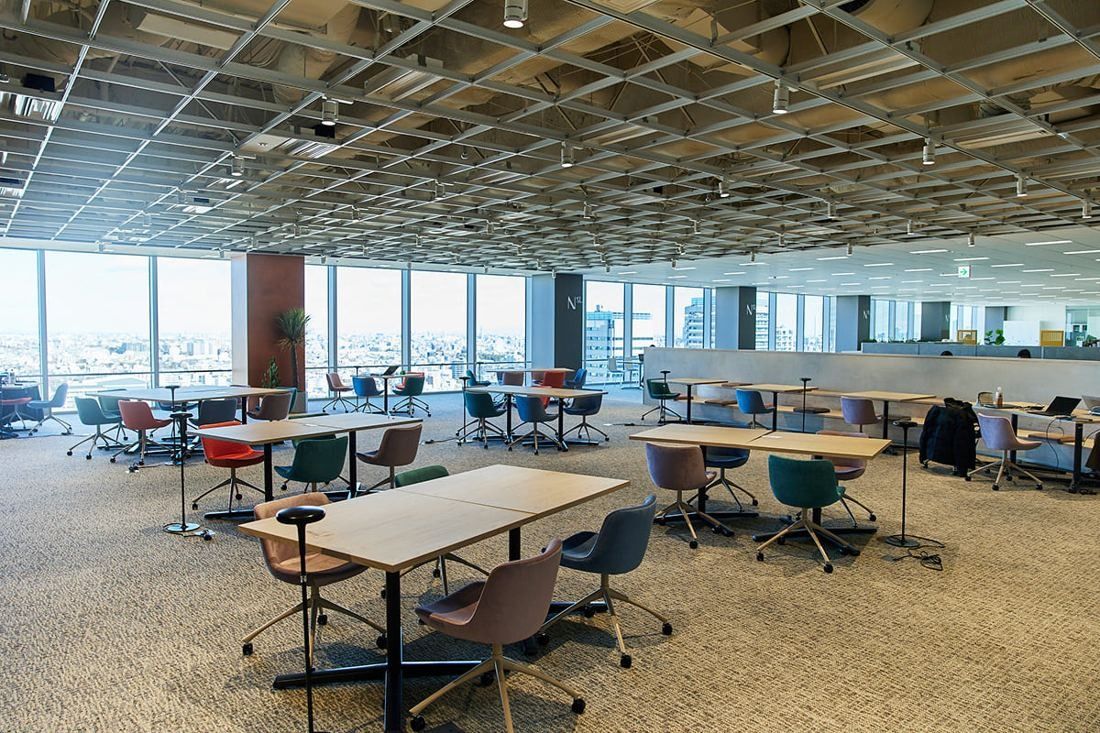 Kirin Holdings: Open floor with exposed grid ceiling, tables and colourful chairs by the windows