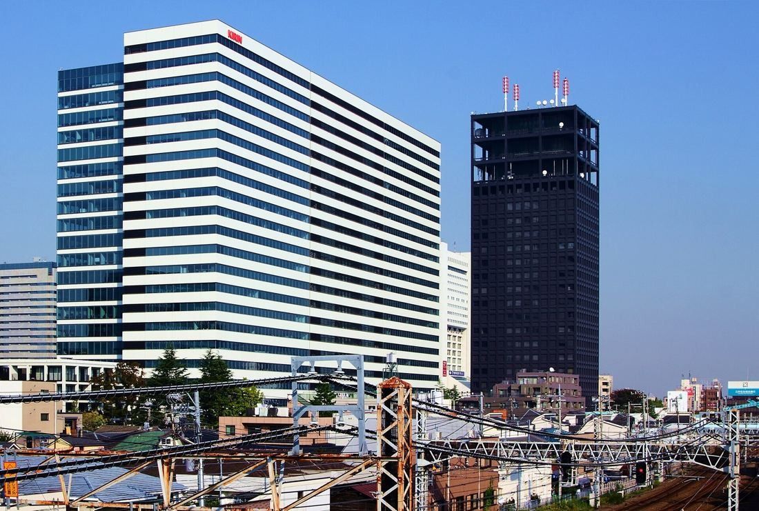 Kirin Holdings: Tower with a KIRIN sign next to a dark high-rise, seen over railway tracks