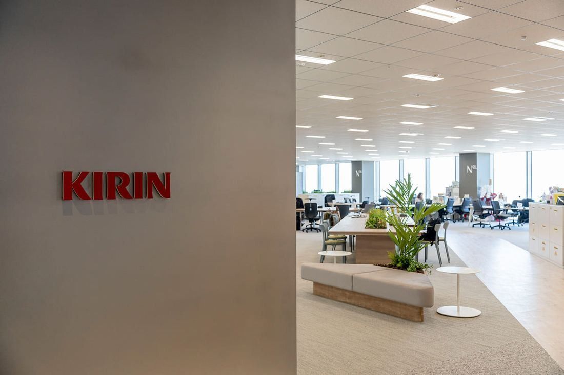 Kirin Holdings: Wall with a red KIRIN logo beside an open office floor with plants