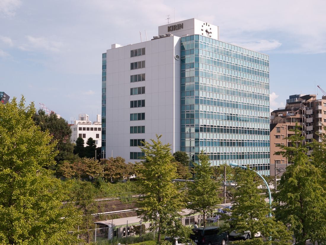 White office building with a glass-clad wing seen above trees