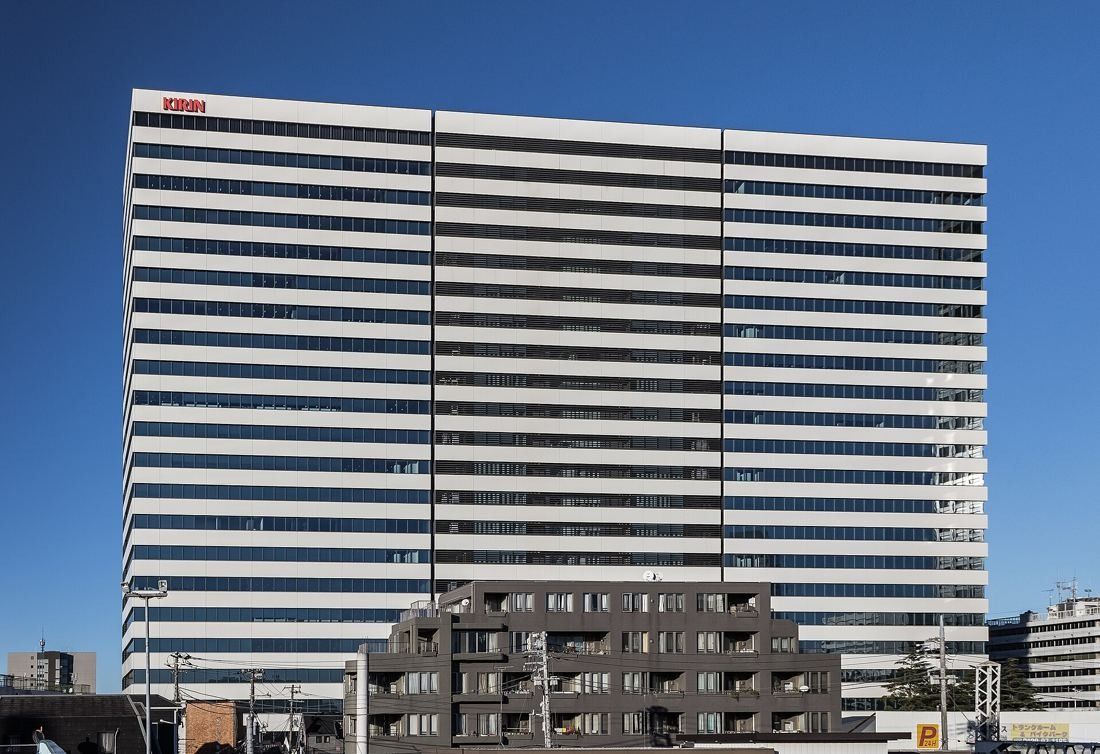 Kirin Holdings: Wide white-striped tower with a KIRIN sign at the top under a blue sky