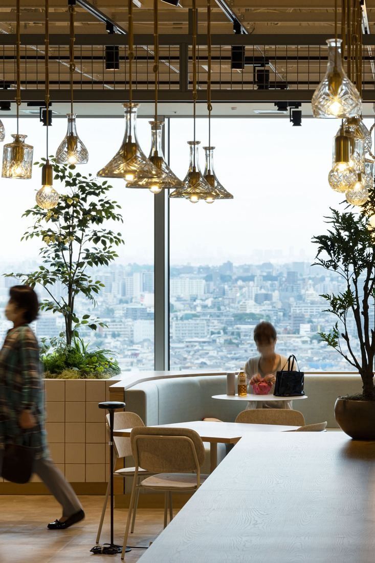 Kirin Holdings: Window-side seating under clusters of glass pendant lamps with a city view