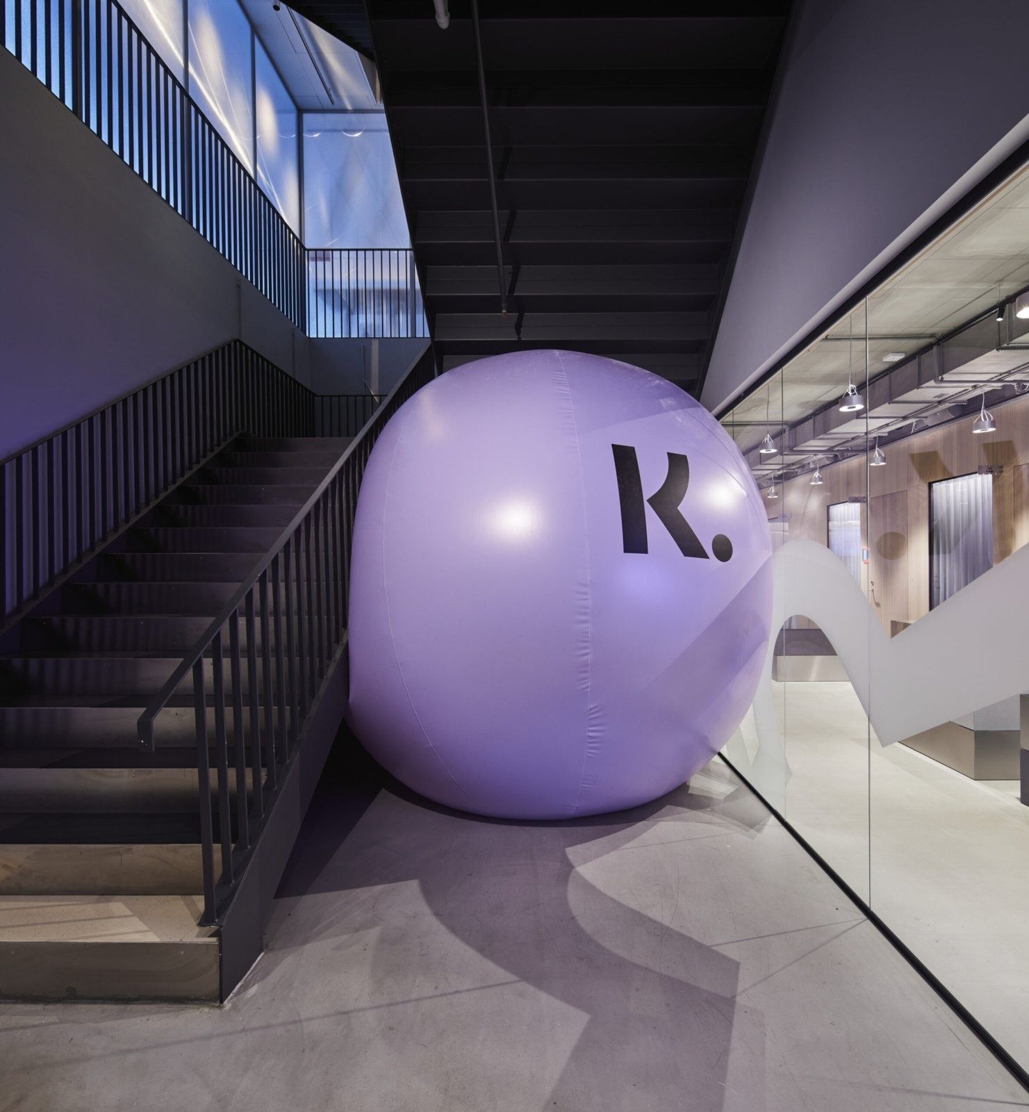 Klarna: Large lilac ball marked with a K beside a dark staircase