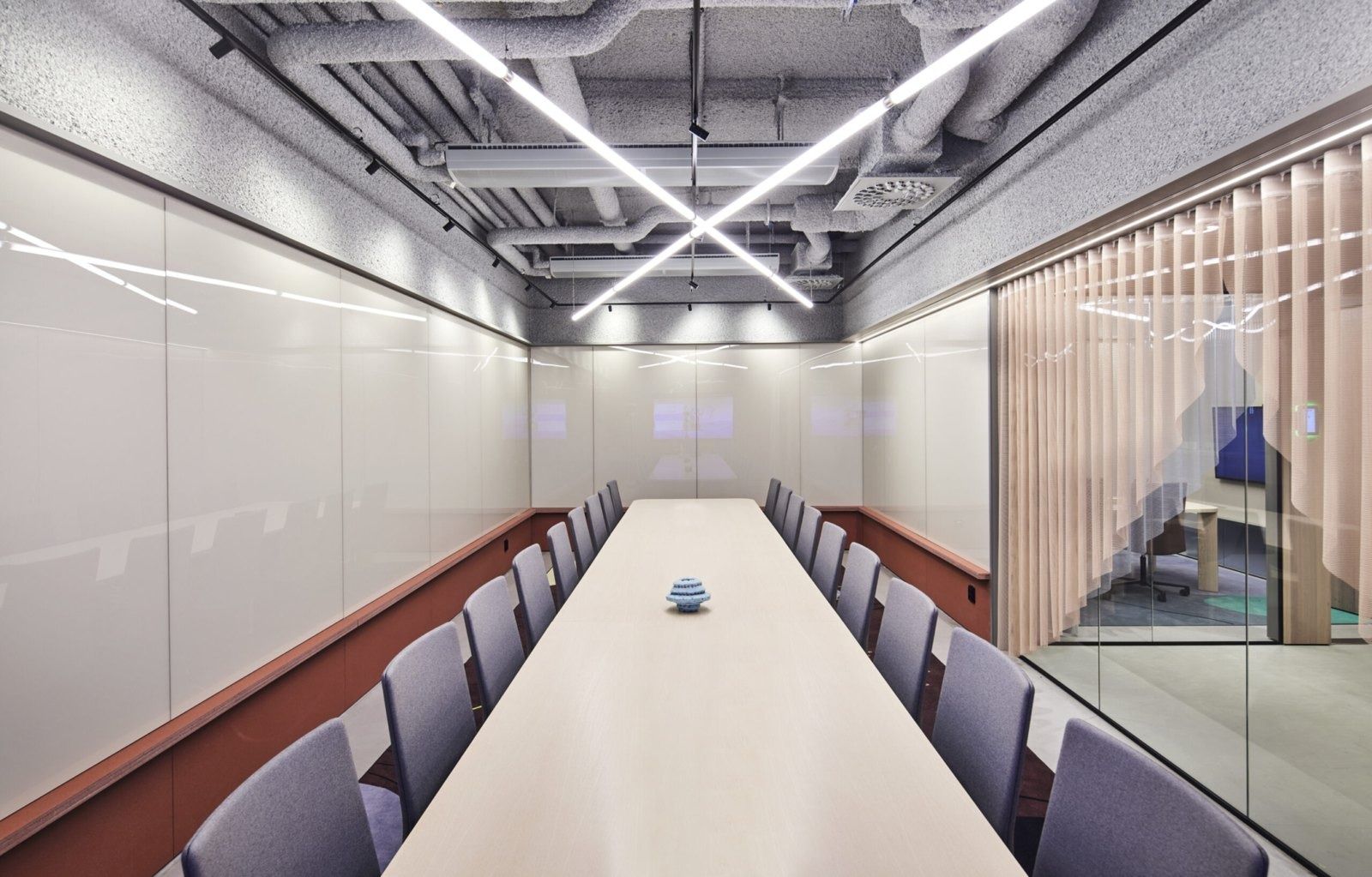 Klarna: Long white conference table with grey chairs under crossing light lines