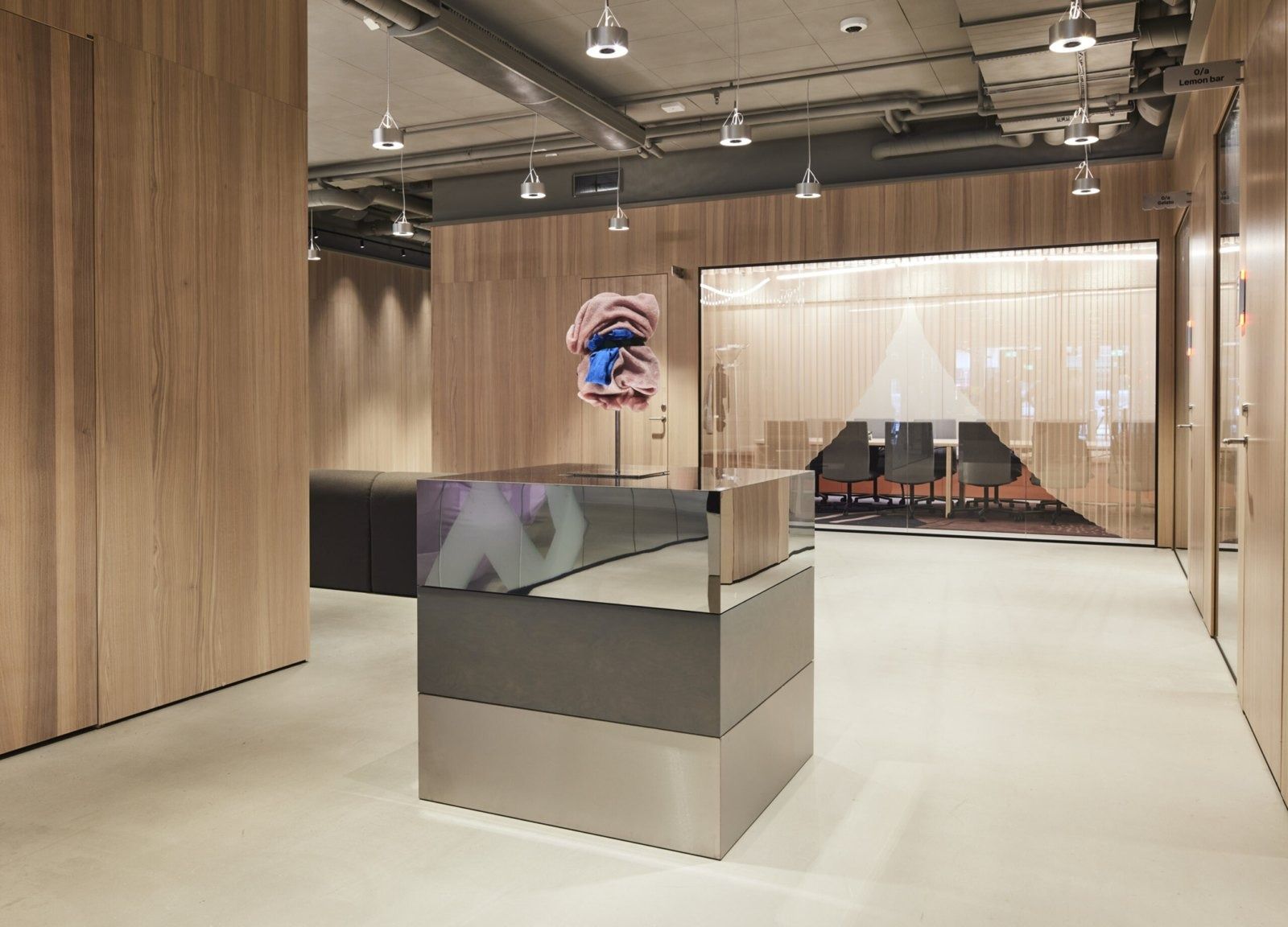 Klarna: Reception-style steel counter between wood-clad walls, with a glass meeting room behind