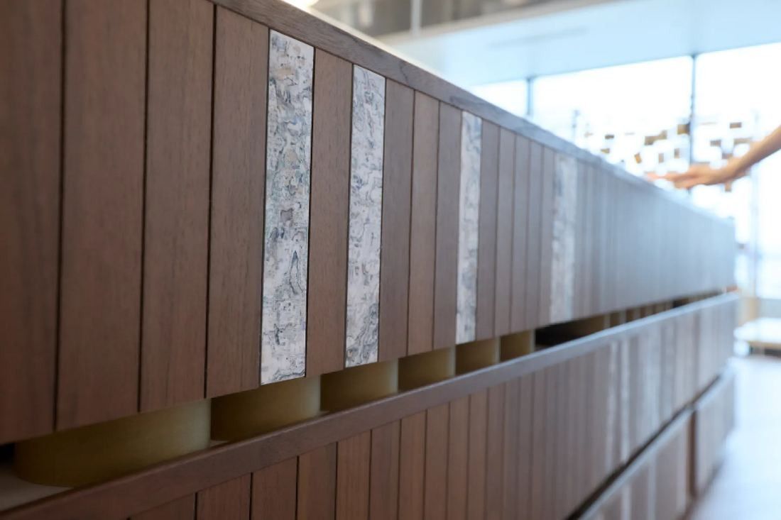 KOKUYO: Close-up of a curved wall of vertical wooden slats with textured inserts
