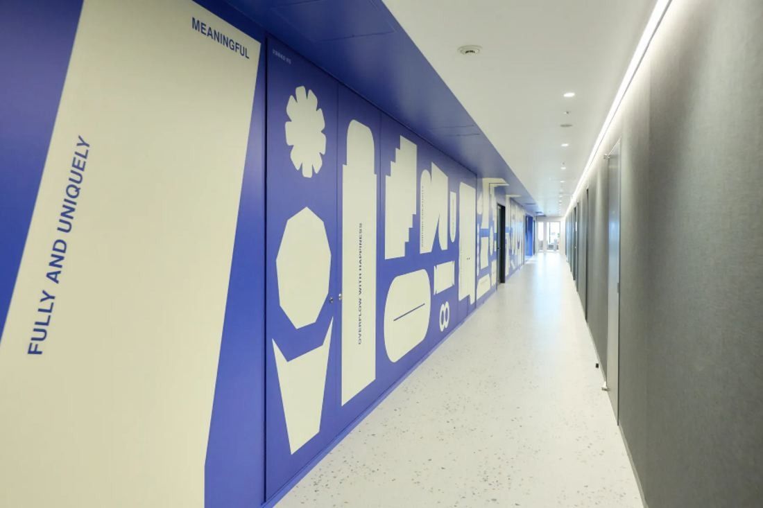 KOKUYO: Long corridor with a large blue and white graphic mural along one wall