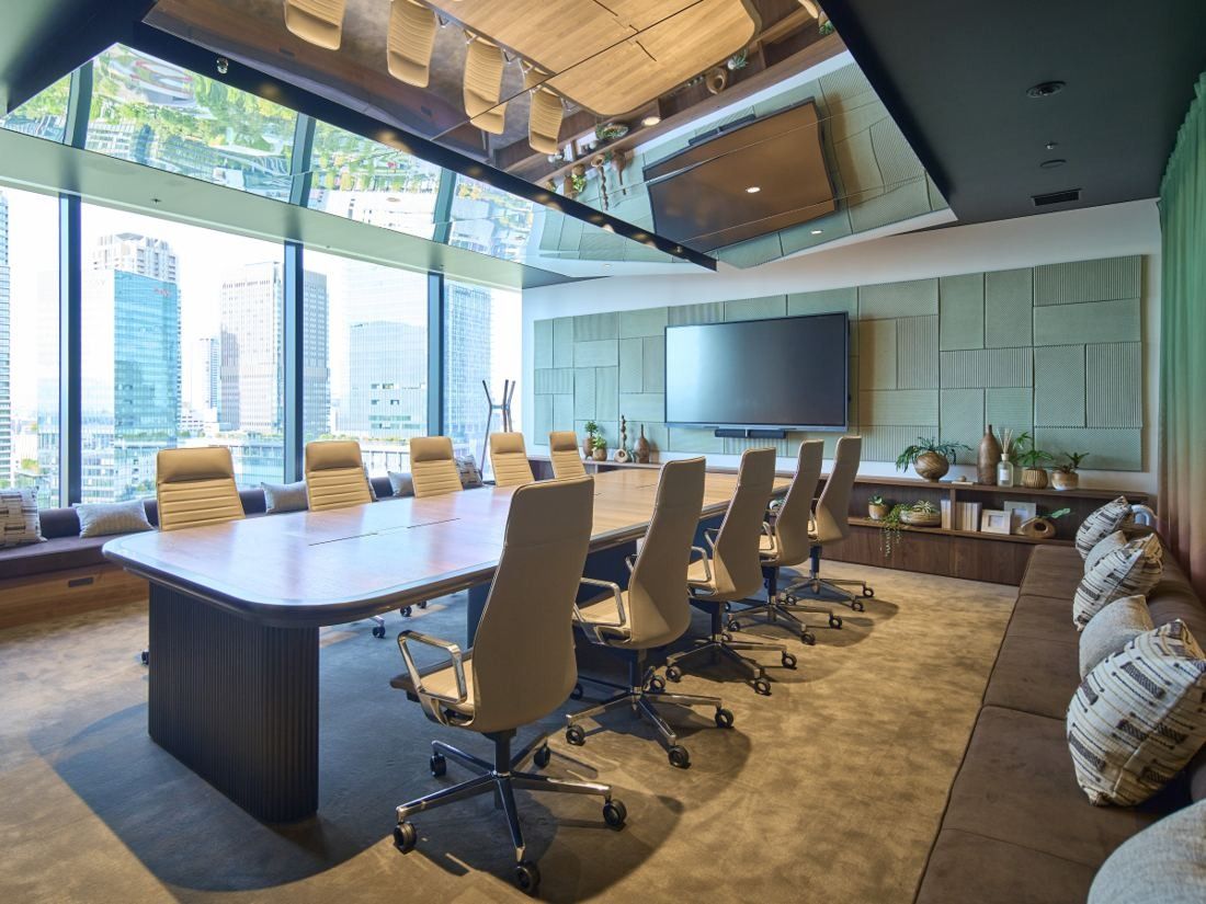 KOKUYO: Meeting room with a long table, beige chairs and floor-to-ceiling windows onto towers