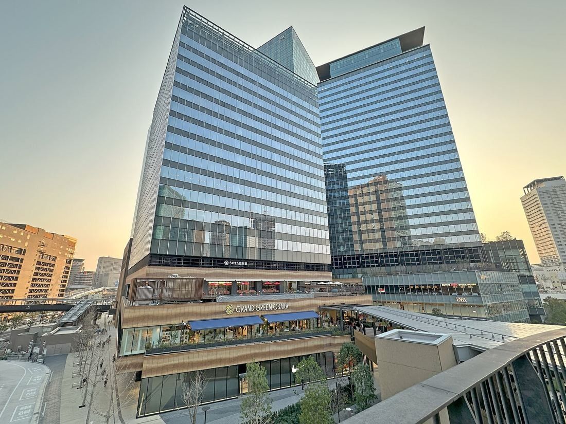 KOKUYO: Two glass office blocks above terraced shops at sunset