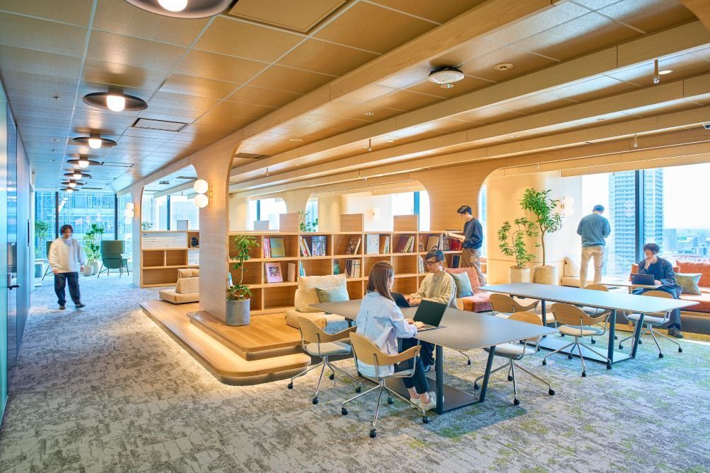 KOKUYO: Wood-panelled area with bookshelves, a stepped platform and long work tables