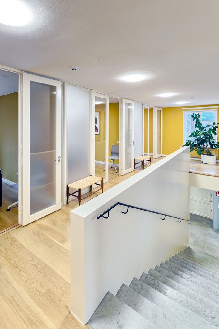 KONE: Bright office corridor with glass doors, yellow walls and a staircase