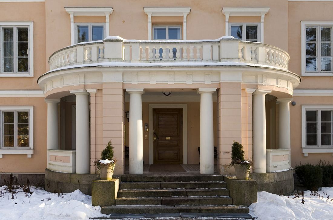 KONE: Columned entrance porch with a balcony above and snow on the ground