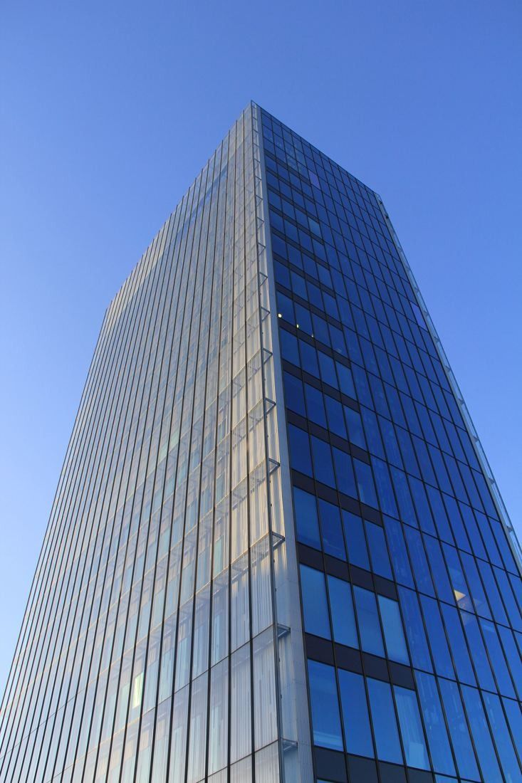 KONE: Corner of a glass tower seen from below against a clear blue sky