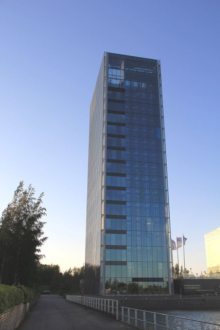 KONE: Glass tower standing at the end of a shoreline path at dusk