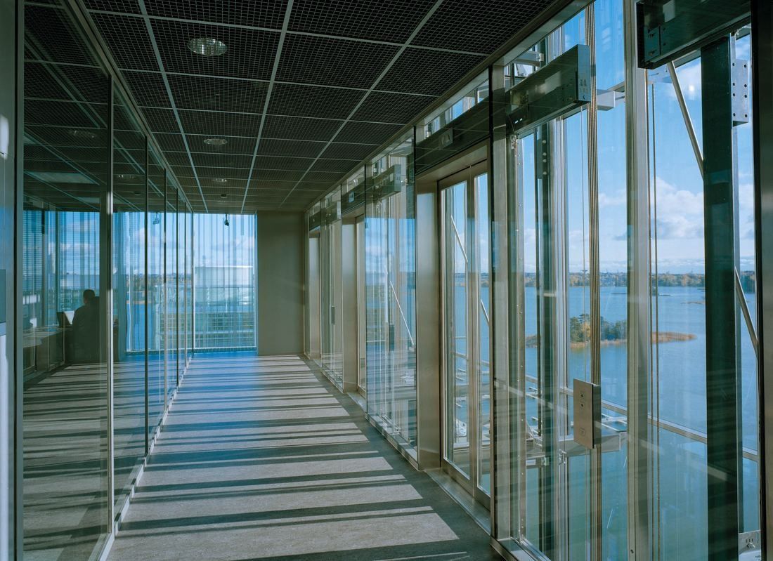 KONE: Long glazed corridor with full-height glass walls and a view of the sea