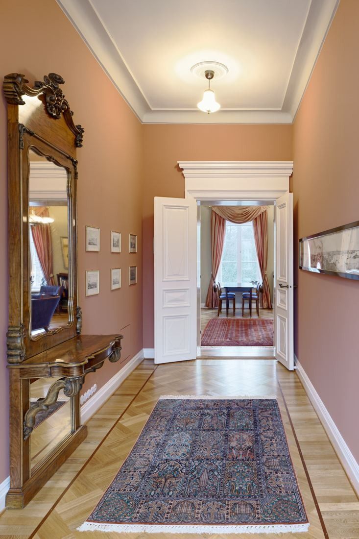 KONE: Manor hallway with a gilded mirror, patterned rug and open double doors