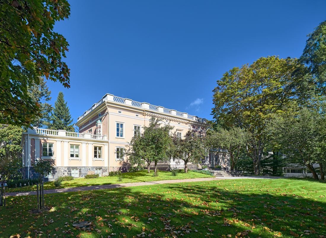 KONE: Manor house seen across a sunny lawn with large trees