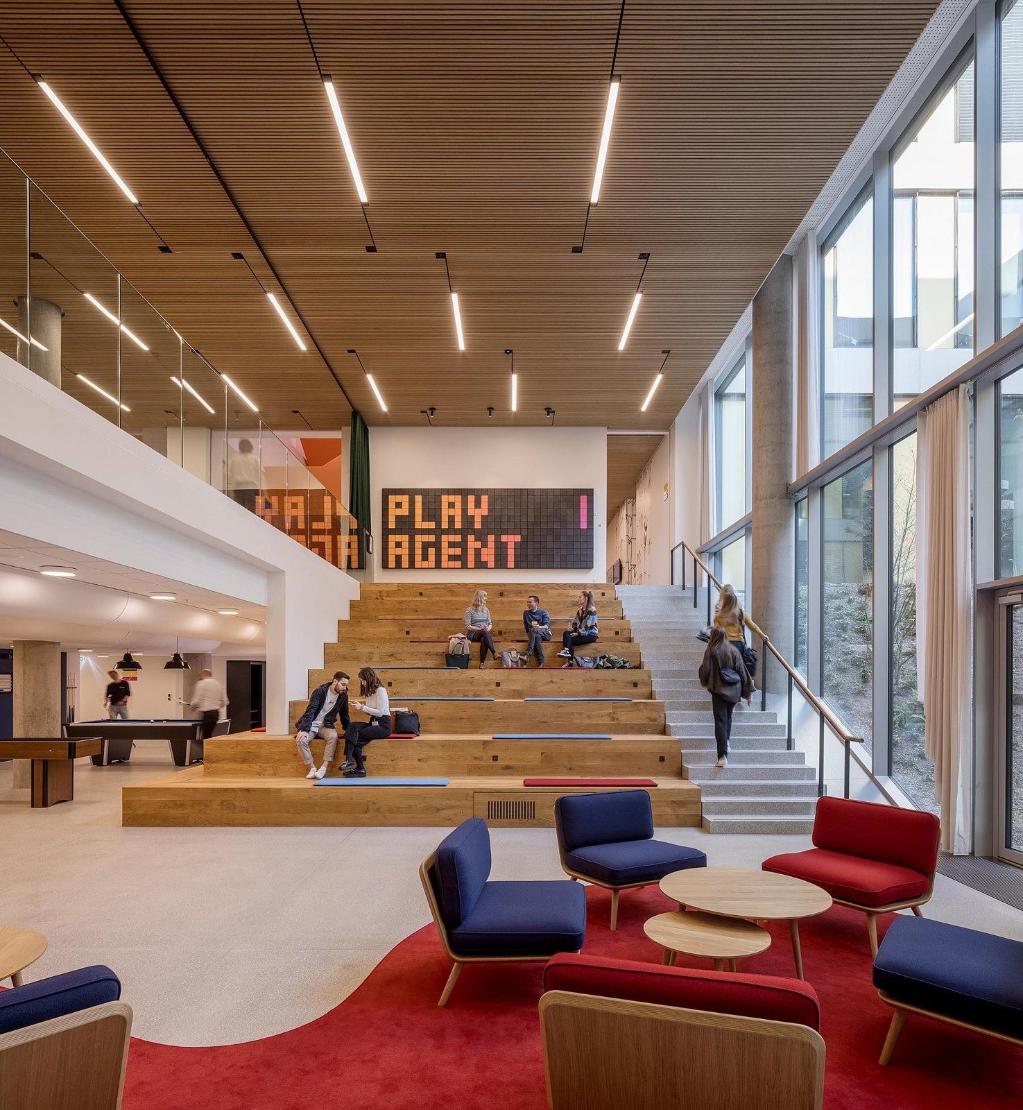 The LEGO Group: Stepped seating and red chairs under a timber ceiling