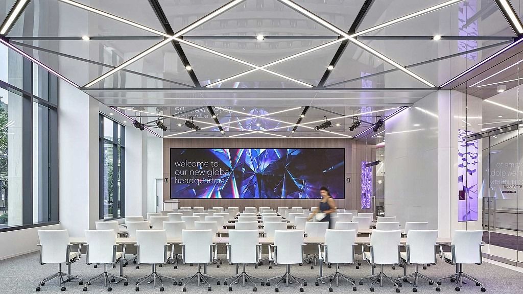Leidos: A large meeting hall with rows of white chairs facing a wide video wall